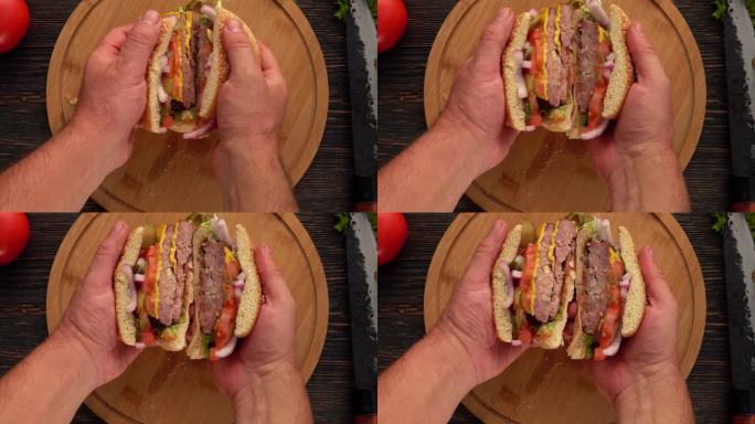 俯视图:男性双手张开的汉堡，肉排切成两半