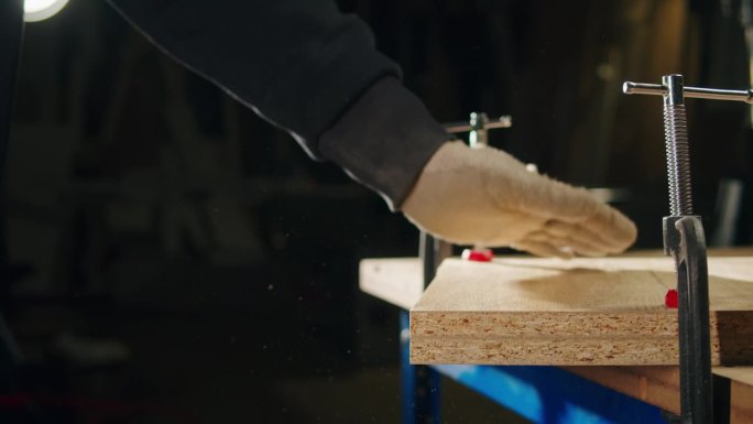 工匠用手用机器打磨木台，男木匠用磨钻设备切割大块木板。