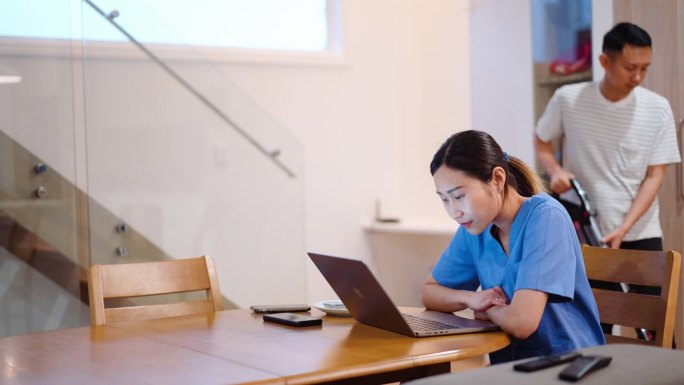 年轻的亚洲医疗保健专业人员穿着手术服在家里开会时用笔记本电脑聊天