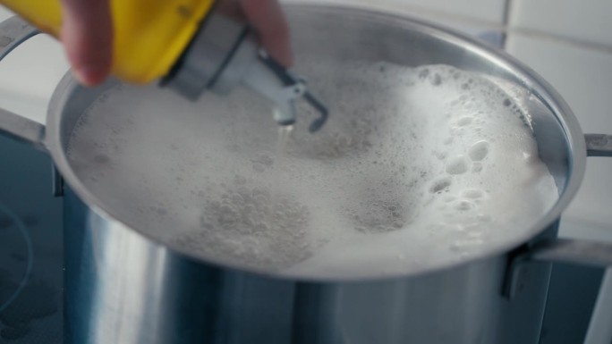 近景——在一天中，用慢动作将橄榄油倒入煮意大利面的大沸水锅中。用索尼FX3拍摄，4K格式。