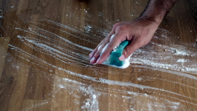用洗涤剂用手擦洗木制桌子。高效清洁:闪闪发光