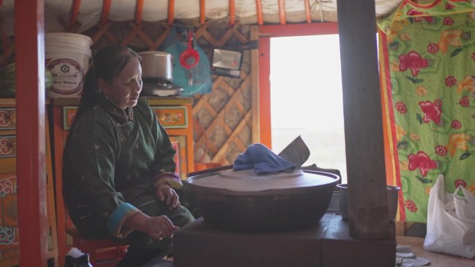 蒙古包内蒙古族牧民妇女为客人准备奶茶