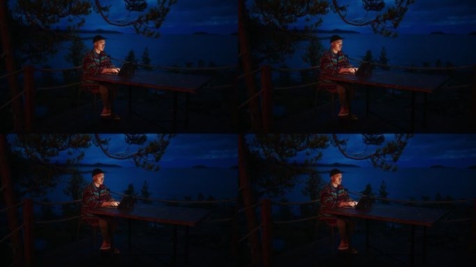 孤独的男人晚上用笔记本上网，独自坐在阳台上发信息