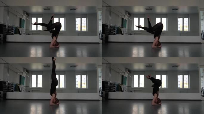 体操女运动员将腿向后拉至头部，在瑜伽房里做伸展运动