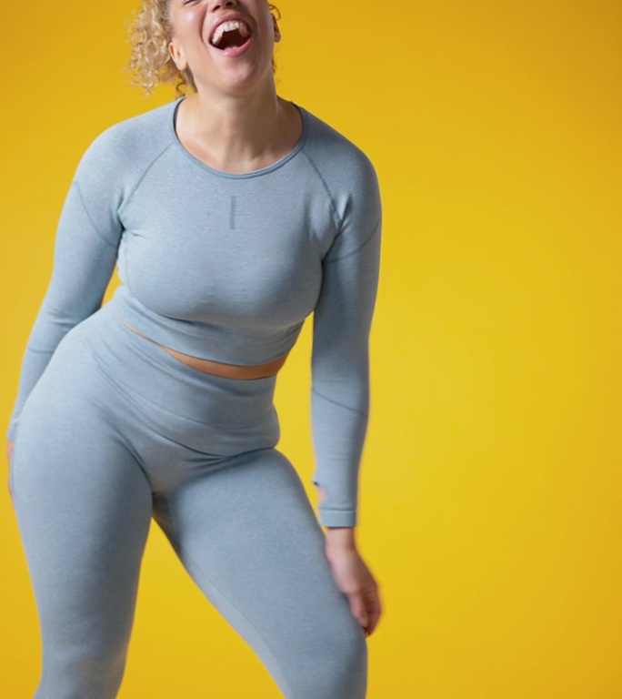 垂直视频工作室拍摄微笑的女人在健身房健身服在黄色背景运动