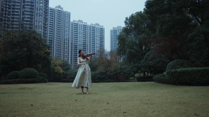 美女在住宅小区草坪上拉小提琴