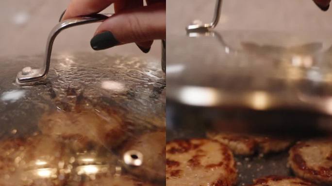 垂直视频。一个女人打开煎锅的盖子，检查汉堡饼是否做好了。锅里的油滋滋作响，肉滋滋作响。缓慢的运动。
