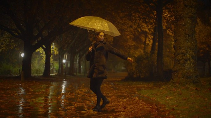 在雨中跳舞的快乐女人们在秋天的公园里享受生活