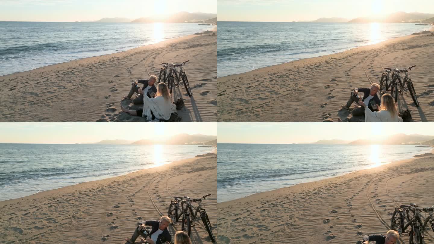 成熟的夫妇在空旷的海滩上喝着普罗塞克