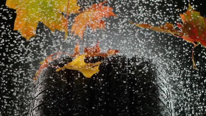 轮胎样品上的雨滴和秋叶的超慢动作