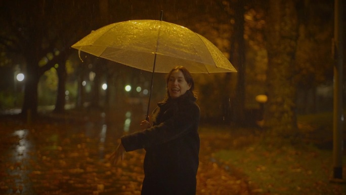 在雨中跳舞的快乐女人们在秋天的公园里享受生活