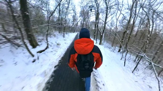 一名身穿红色夹克的男子走过冬天积雪的森林