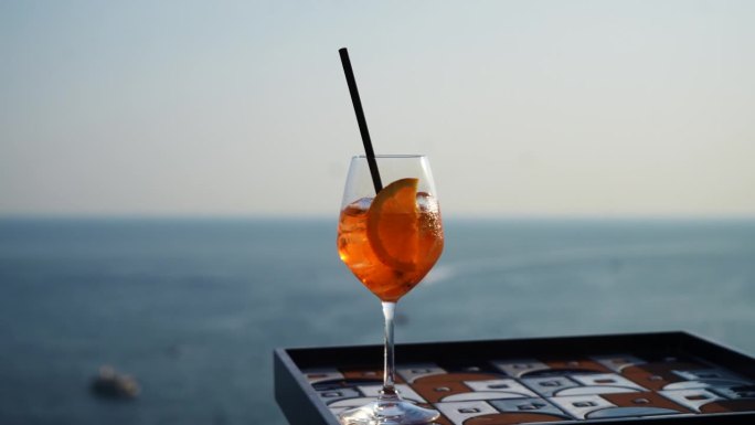 夏天阳光明媚的日子里，以美丽的海景为背景的玻璃杯与Aperol Spritz(由prosecco, 