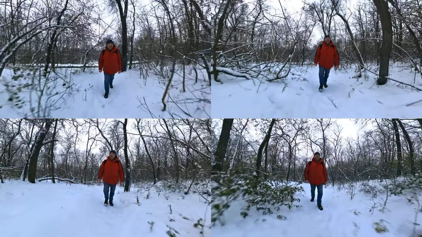 一名身穿红色夹克的男子走过冬天积雪的森林