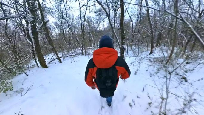 一名身穿红色夹克的男子走过冬天积雪的森林