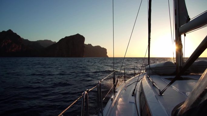 一艘帆船正驶向夕阳。阳光照亮了白色的帆船。在海上航行。从船上看日落的美丽景色。4 k。