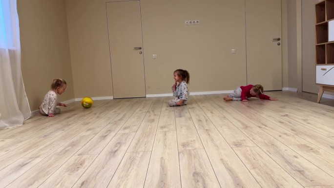 在家里和三胞胎小姐妹玩躲避球游戏，球飞了起来，击中了一个穿着睡衣的女孩