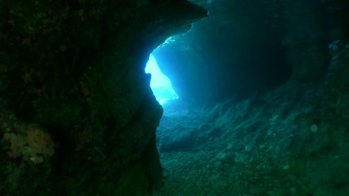 摄像机穿过阳光幕进入水下的石头隧道。