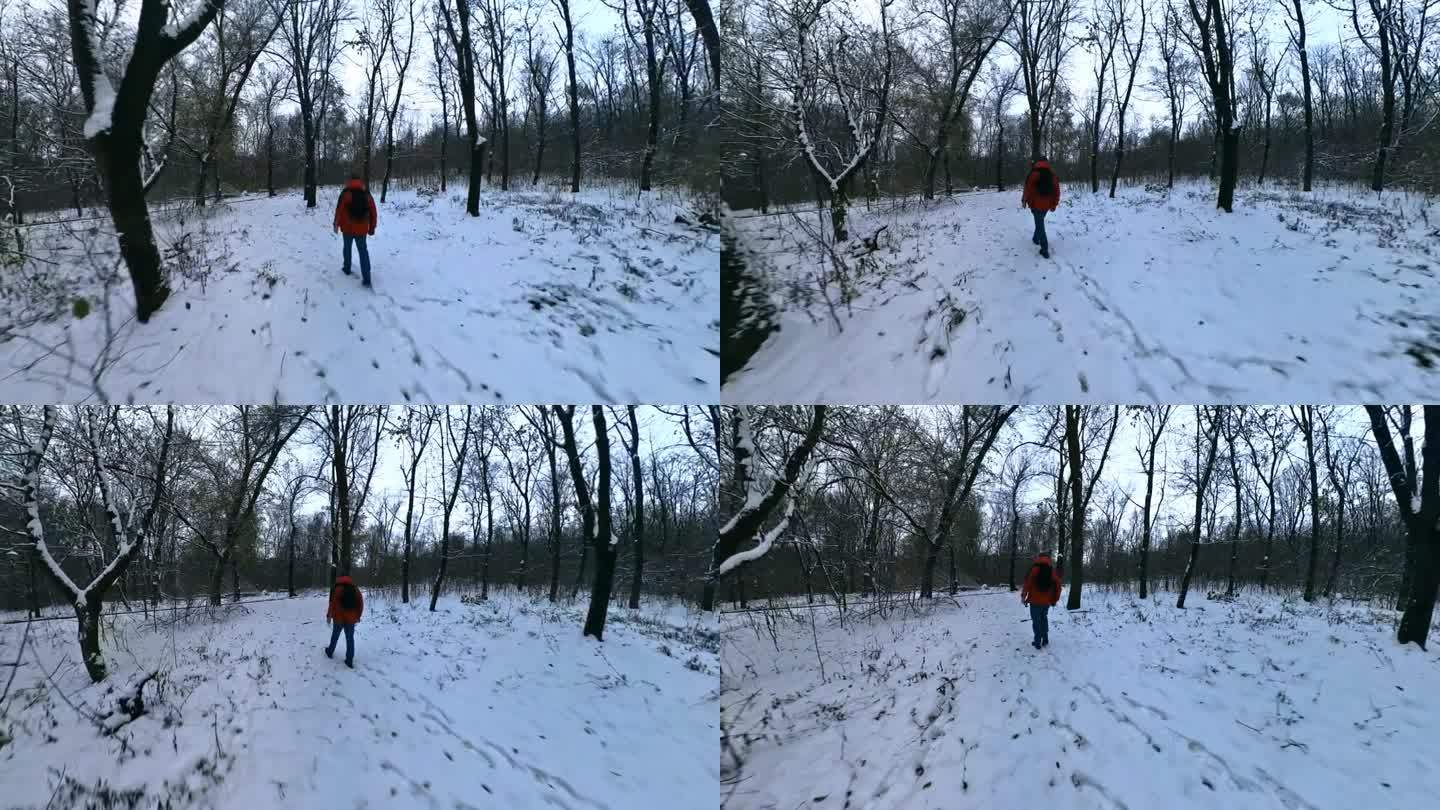 一名身穿红色夹克的男子走过冬天积雪的森林