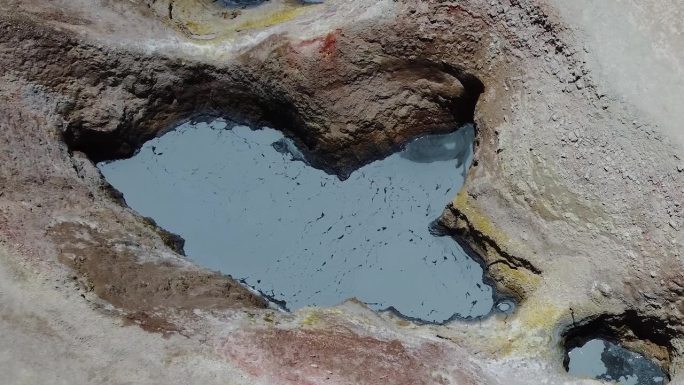 大池的灰色泥浆冒泡通过热通风口在地面上俯瞰