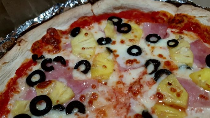 夏威夷披萨配菠萝火腿奶酪和黑橄榄近距离拍摄家庭烘焙意大利融合食品4k