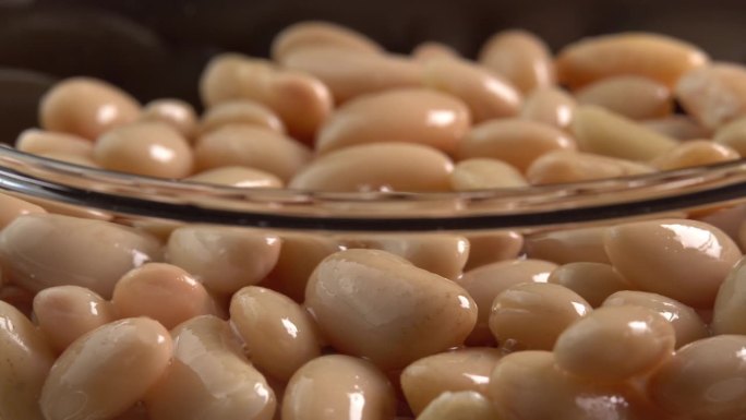 白芸豆罐头在玻璃碗里旋转。有机蒸豆。墨西哥菜的腌豆