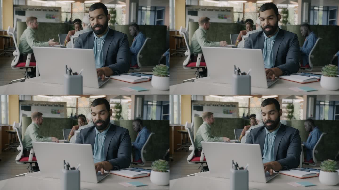 雄心勃勃的阿拉伯人坐在现代联合办公中心的办公桌前用笔记本电脑打字