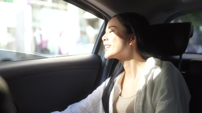 放松的感觉，女人坐在汽车后座系安全带，看着窗外。女开心在车里旅行，在去目的地的路上坐出租车。