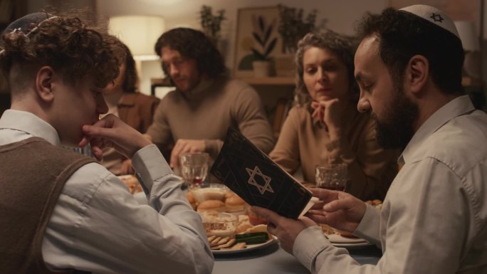 犹太男子在光明节宴会上向家人朗读《摩西五经》