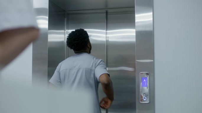 非裔美国医生按下电梯呼叫按钮