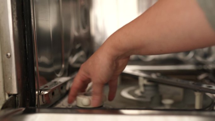 妇女使用洗碗机，将盐倒入专用容器中