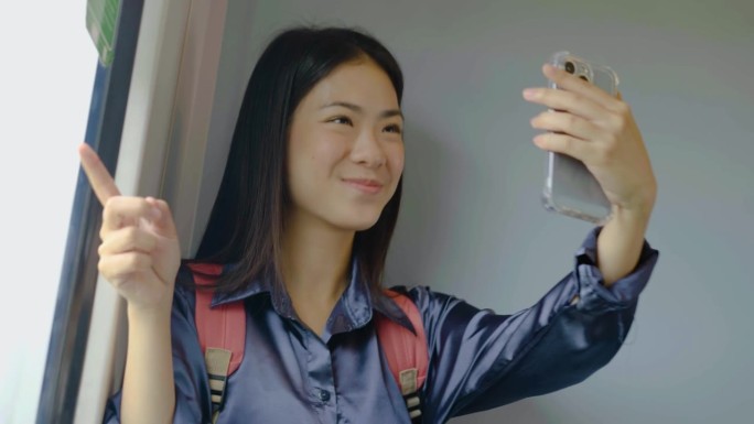 年轻美丽的亚洲女游客挥手，在线聊天，手机视频通话，签到，社交媒体发帖，旅游城市火车交通，快乐之旅度假