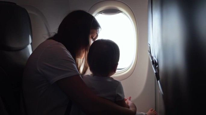 妈妈和孩子坐飞机，妈妈从窗户看风景