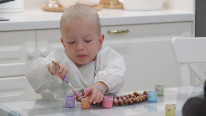 蹒跚学步的孩子用手指颜料在画橡子项链