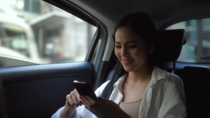 女性坐在汽车后座系上安全带，在出租车上使用智能手机的放松感觉。女开心在车里旅行，在去目的地的路上坐出