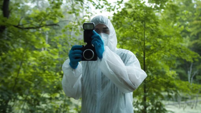 犯罪学家在森林犯罪现场拍照，使用专业相机，从事故中获取证据。调查证据，法医鉴定。侦探，法医