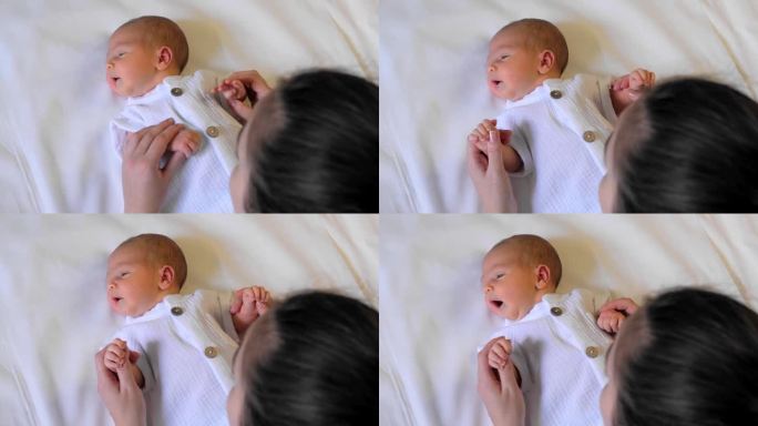 一个可爱的新生婴儿的特写肖像。一位年轻妇女双手抱着一个婴儿。母子之间的沟通，爱与关怀。