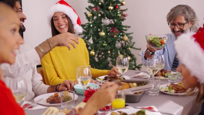 圣诞午餐时，一家人欢声笑语地围坐在餐桌旁。家庭生活的人。