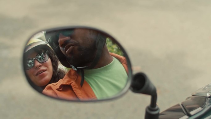 男人和女人骑摩托车时后视镜里的倒影
