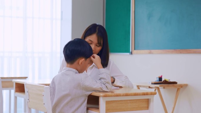 亚洲美女女老师在教室里教小男生。在幼儿园，有魅力的女教师在课堂上给孩子们讲解和教育课程。