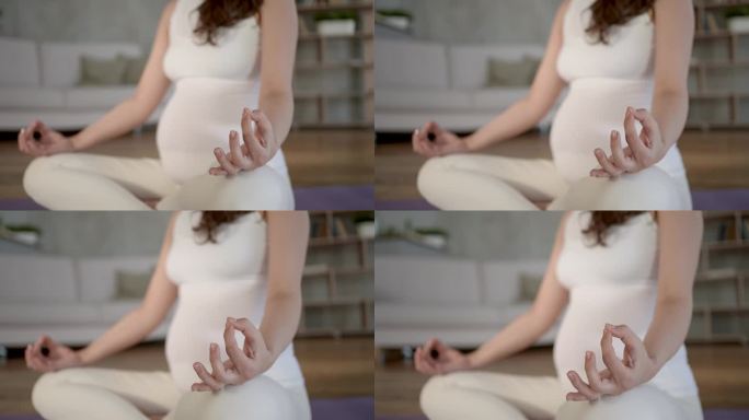 年轻的孕妇坐在地板上，在室内做瑜伽莲花式。运动锻炼孕妇理念放松健康生活方式。孕妇呼吸平静瑜伽练习呼吸