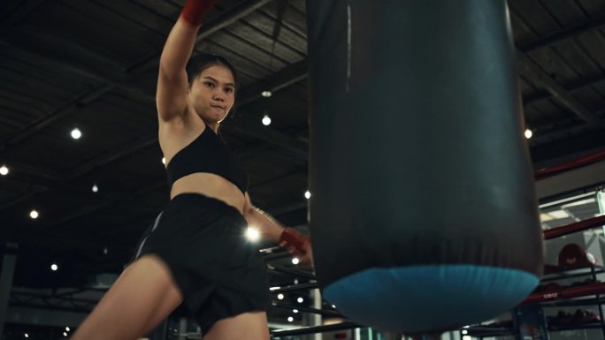 年轻的女拳手训练出拳，打沙袋，在拳击馆训练一天，力量强健身体，女孩打得快。