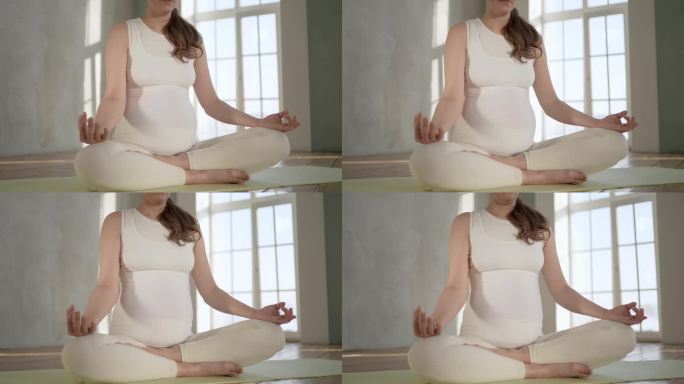 无法辨认的孕妇坐在地板上做瑜伽莲花式室内特写。生育理念放松健康生活方式。孕妇呼吸平静瑜伽练习呼吸冥想