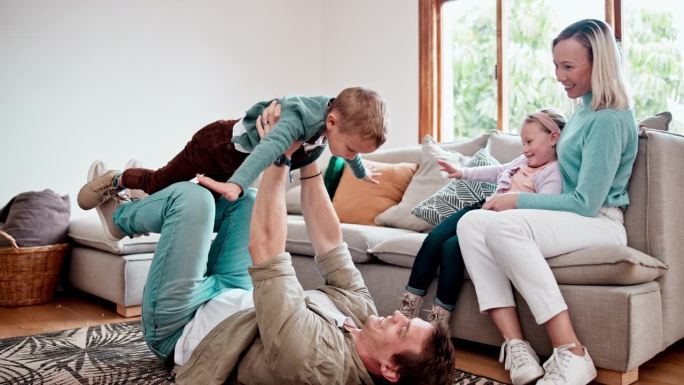 开心的时候，孩子们和父母一起在客厅的沙发上玩耍。微笑，玩耍，孩子们在家里的休息室里和父母一起坐飞机。