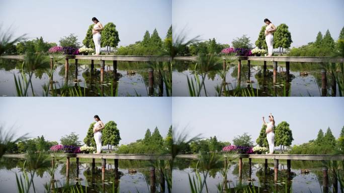 孕妇美女在夏日清晨湖边抚摸肚子晨练瑜伽