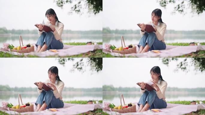 一个亚洲女人在休息日在池塘边野餐，一边看书一边听音乐。一个宁静的湖边时刻，完美的休闲和放松的内容。