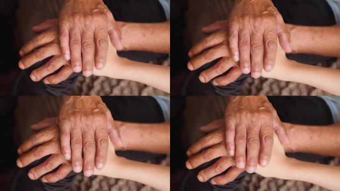 照顾老人的家庭观念。孙子或孙女的手抚摸着祖父布满皱纹的手。亲情在，老人在
