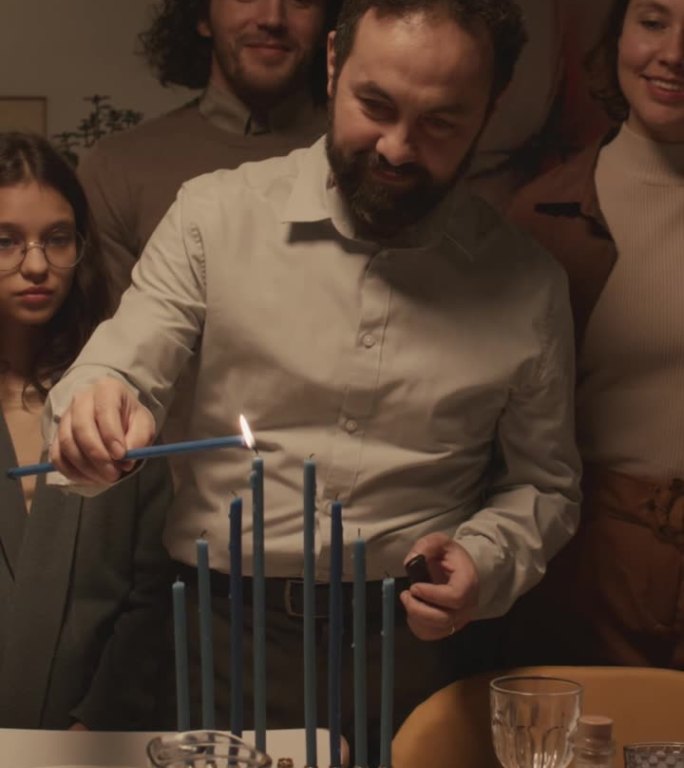 犹太男子在哈努克节点燃蜡烛，孩子们在观看