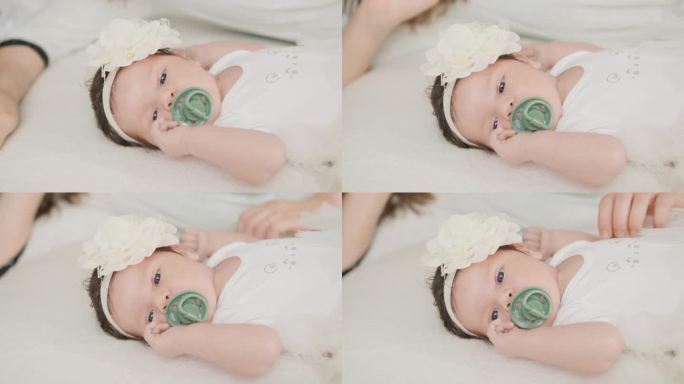 新生儿头戴花蝴蝶结躺在母亲的婴儿床里