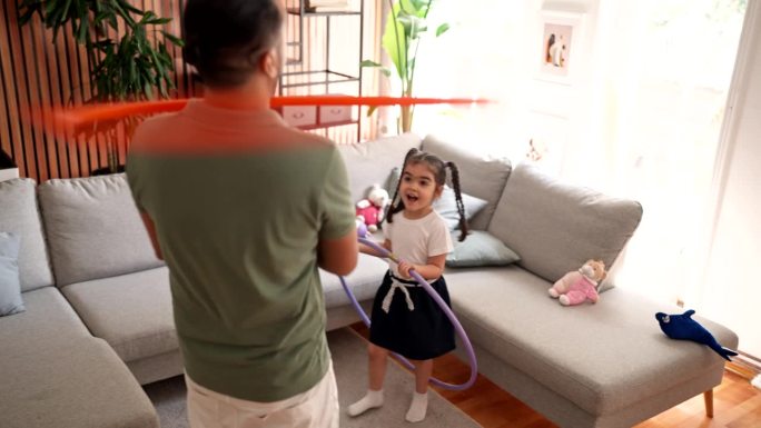 父亲和女儿在家里玩呼啦圈